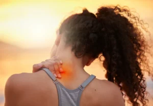 Frau mit Nackenschmerzen bei Sonnenuntergang